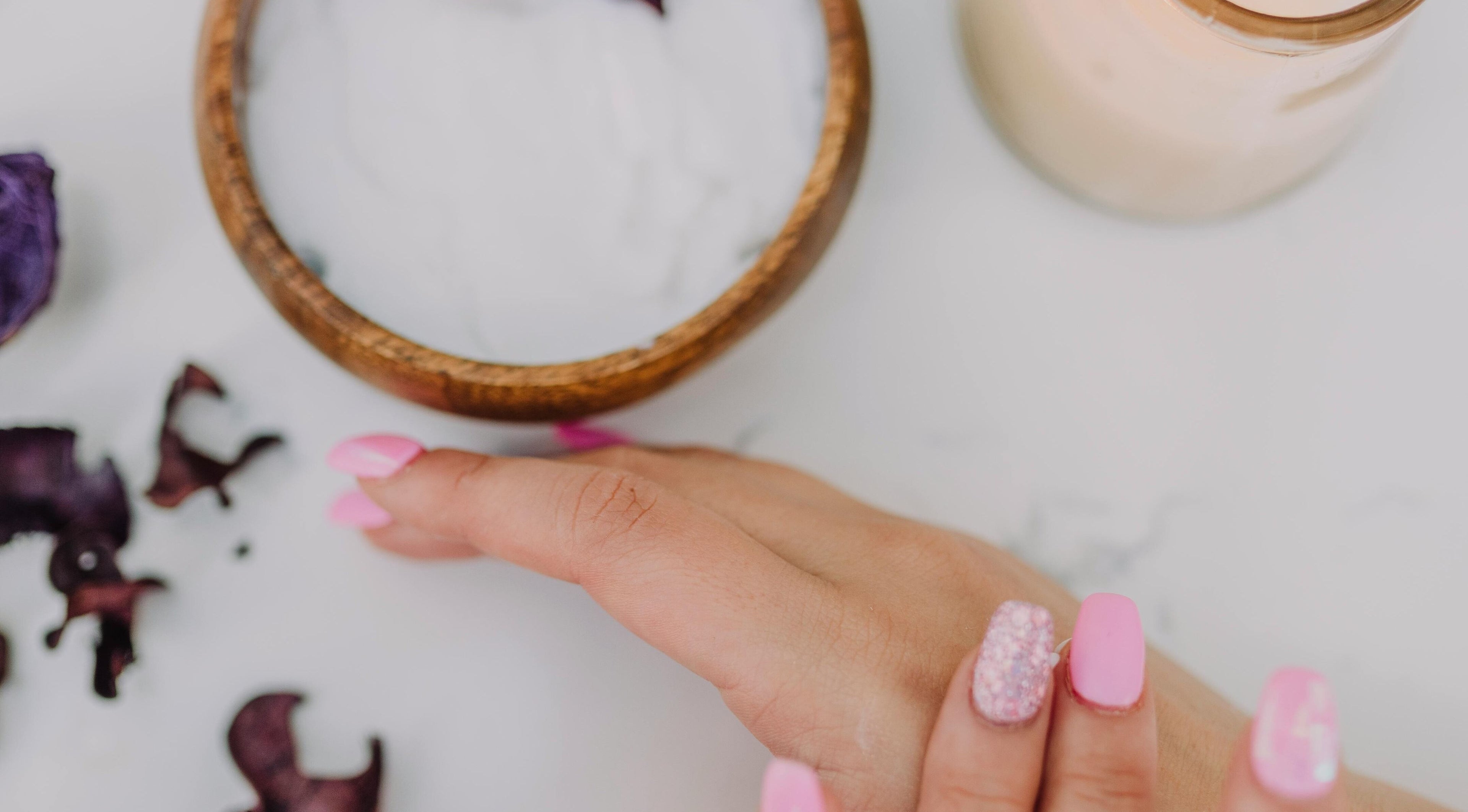 Manicura rosa en Luxotio, Barcelona, Catalunya, ES, junto a crema y flores decorativas.