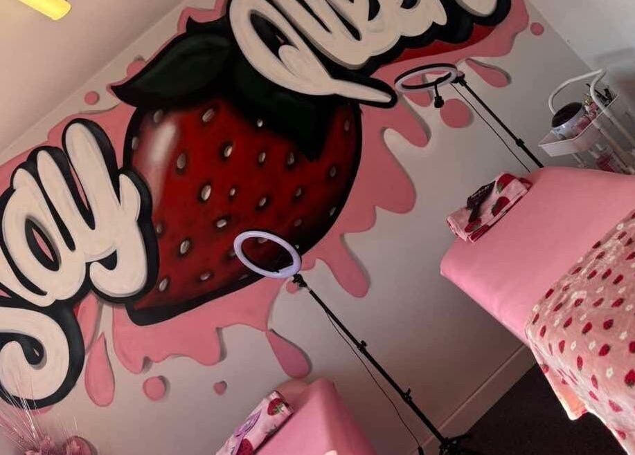 Vibrant strawberry wall art in Byloganjanesalon, Houghton Le Spring, England. Inviting pink decor and treatment table.