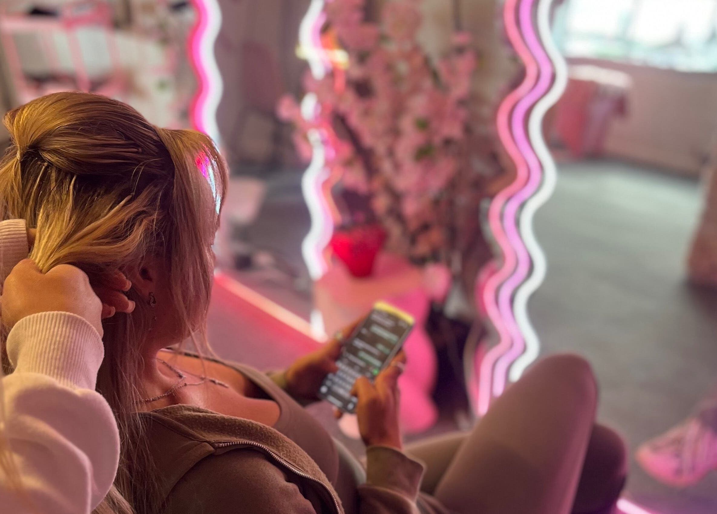 Woman enjoys a salon experience at Byloganjanesalon, Houghton Le Spring, England with neon-lit mirrors.