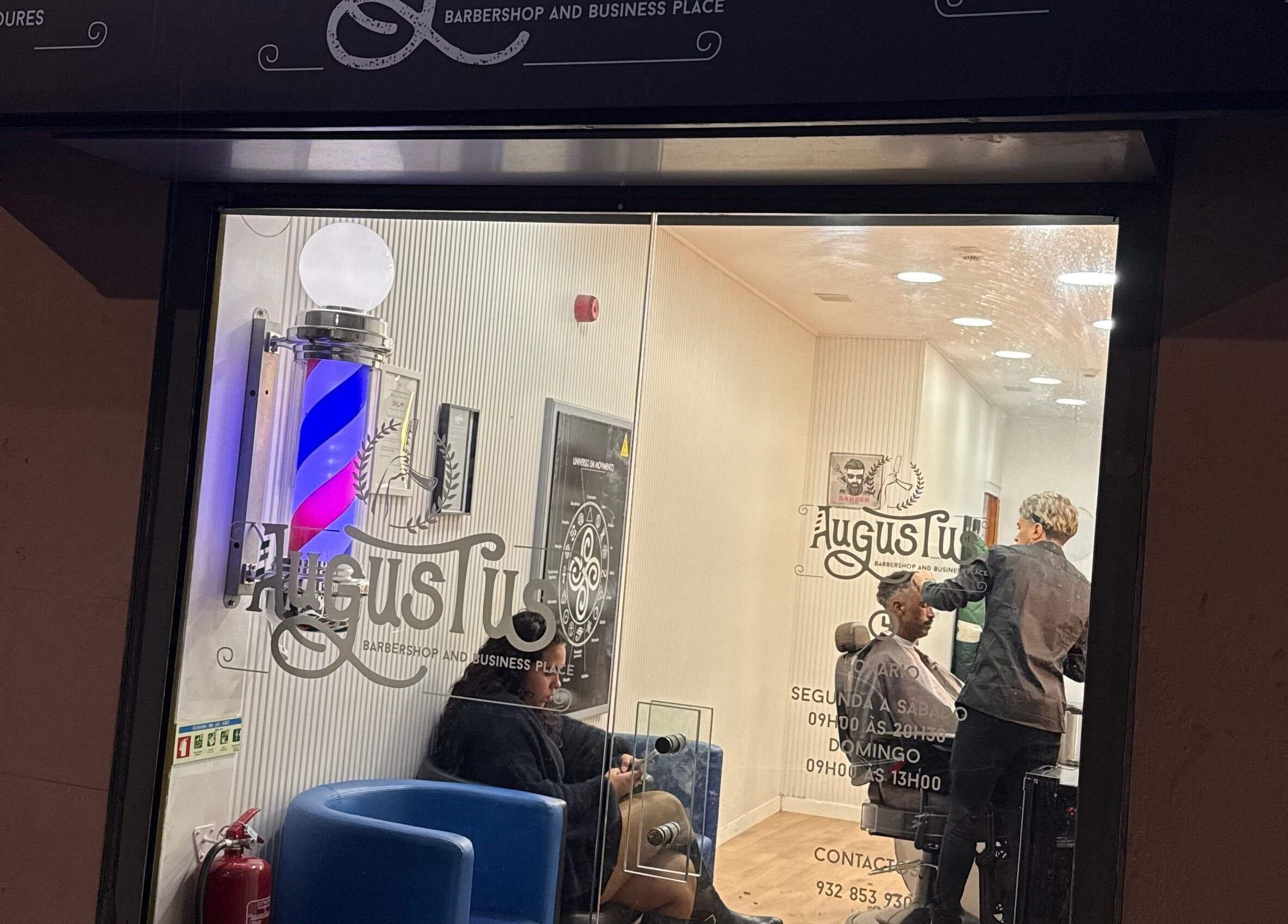Vista noturna da Barbearia Augustus Loures em Loures, Lisboa, PT, mostrando clientes e cabeleireiro em ação.