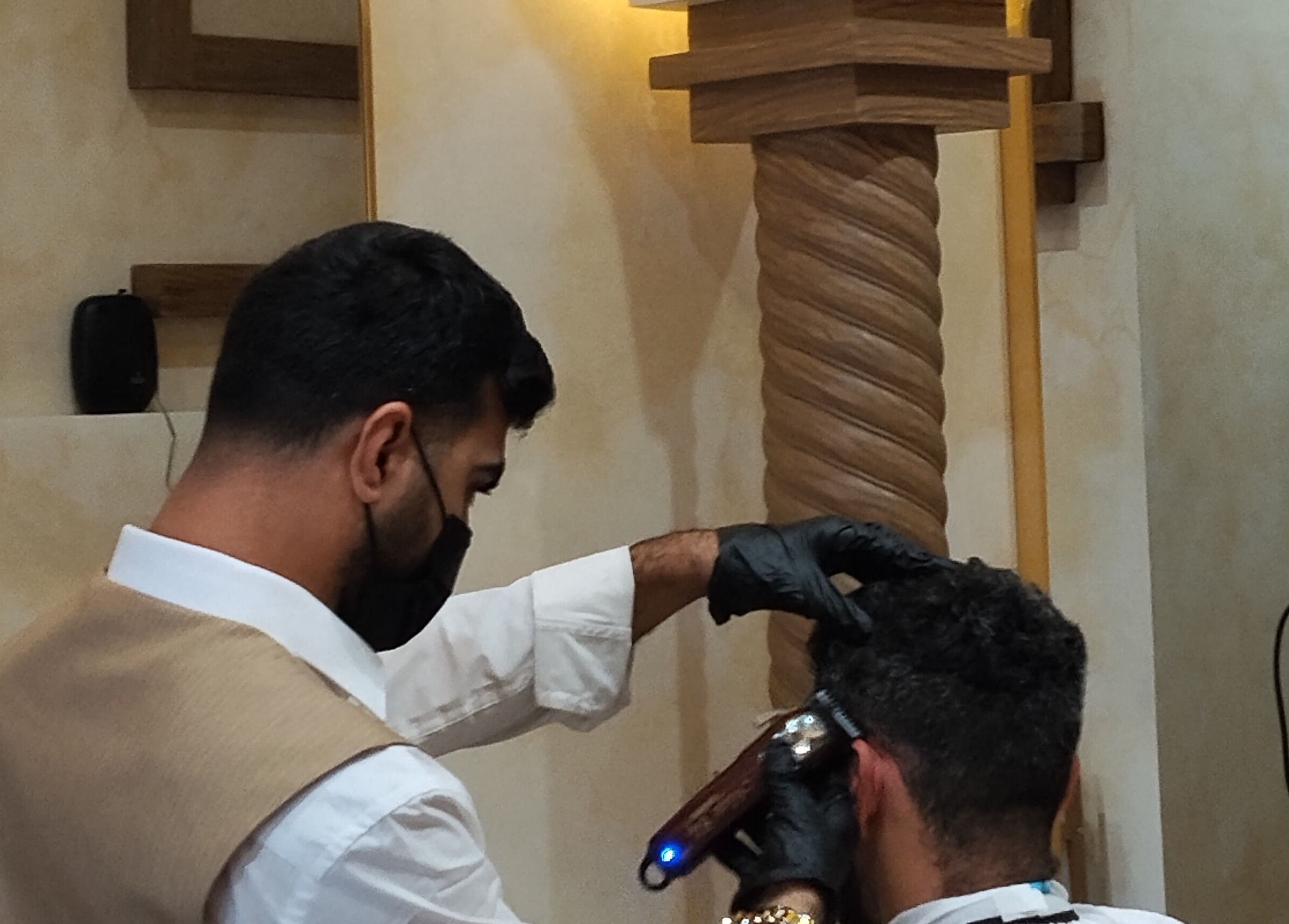 Barber at حلاق مشط الجزيرة in Riyadh providing a stylish haircut in a modern setting.