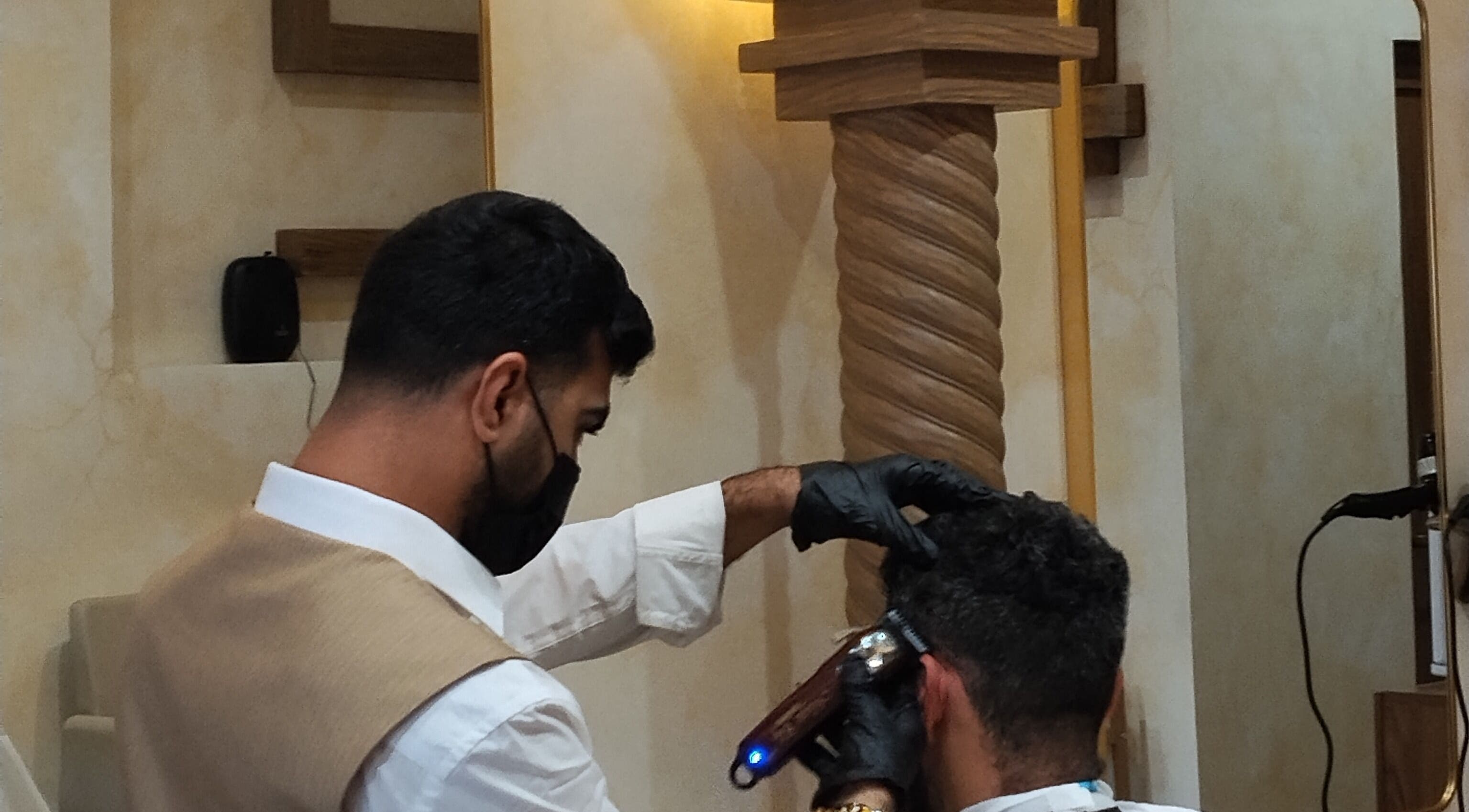 Barber at حلاق مشط الجزيرة in Riyadh providing a stylish haircut in a modern setting.