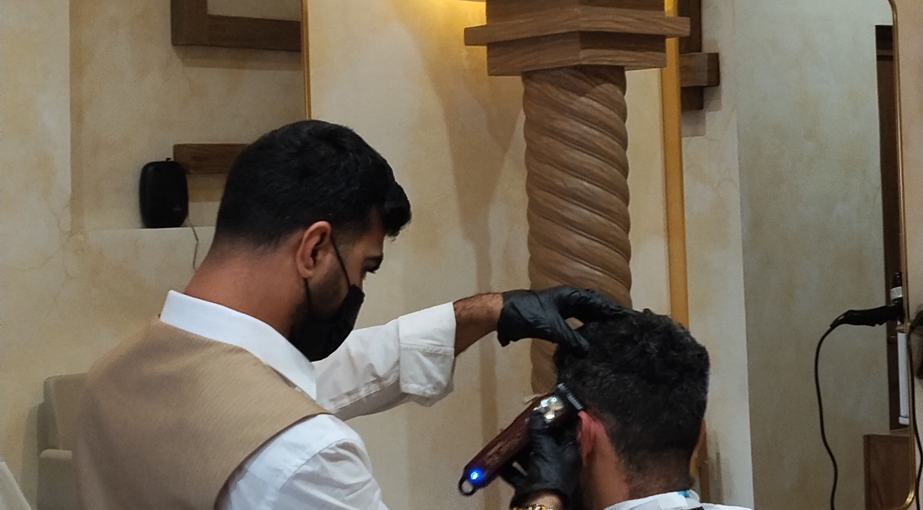 Barber at حلاق مشط الجزيرة in Riyadh providing a stylish haircut in a modern setting.