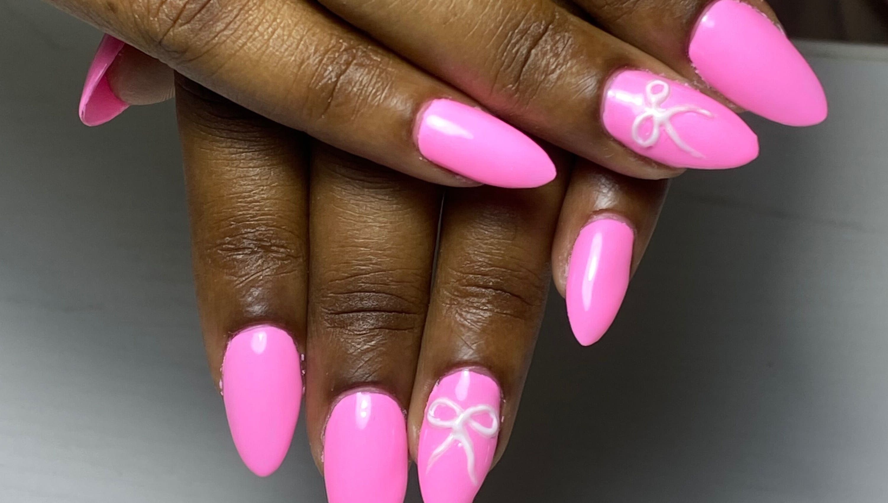 Bright pink nails with bow detail at Glossy in Paramaribo, Paramaribo, SR.