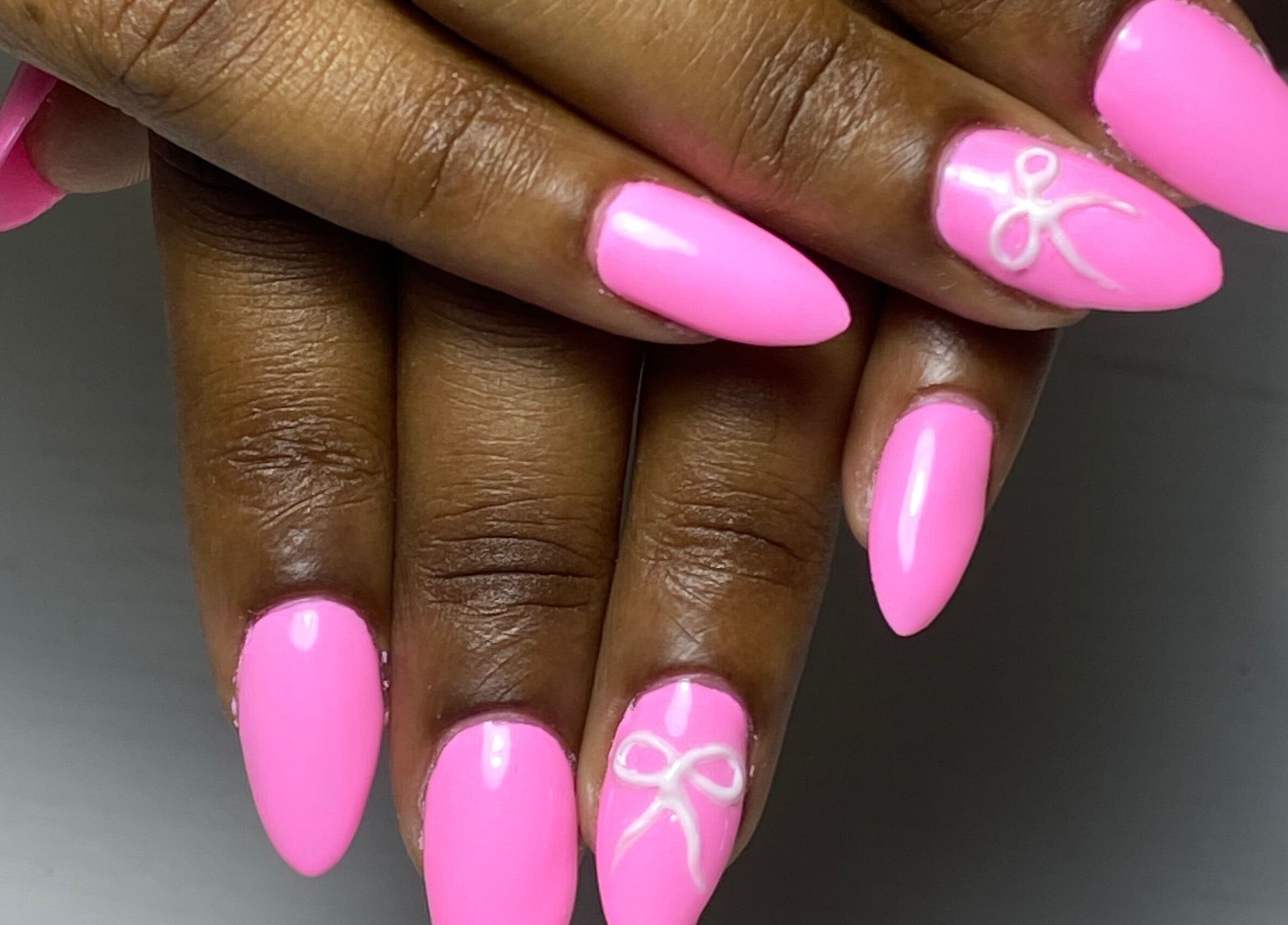 Bright pink nails with bow detail at Glossy in Paramaribo, Paramaribo, SR.