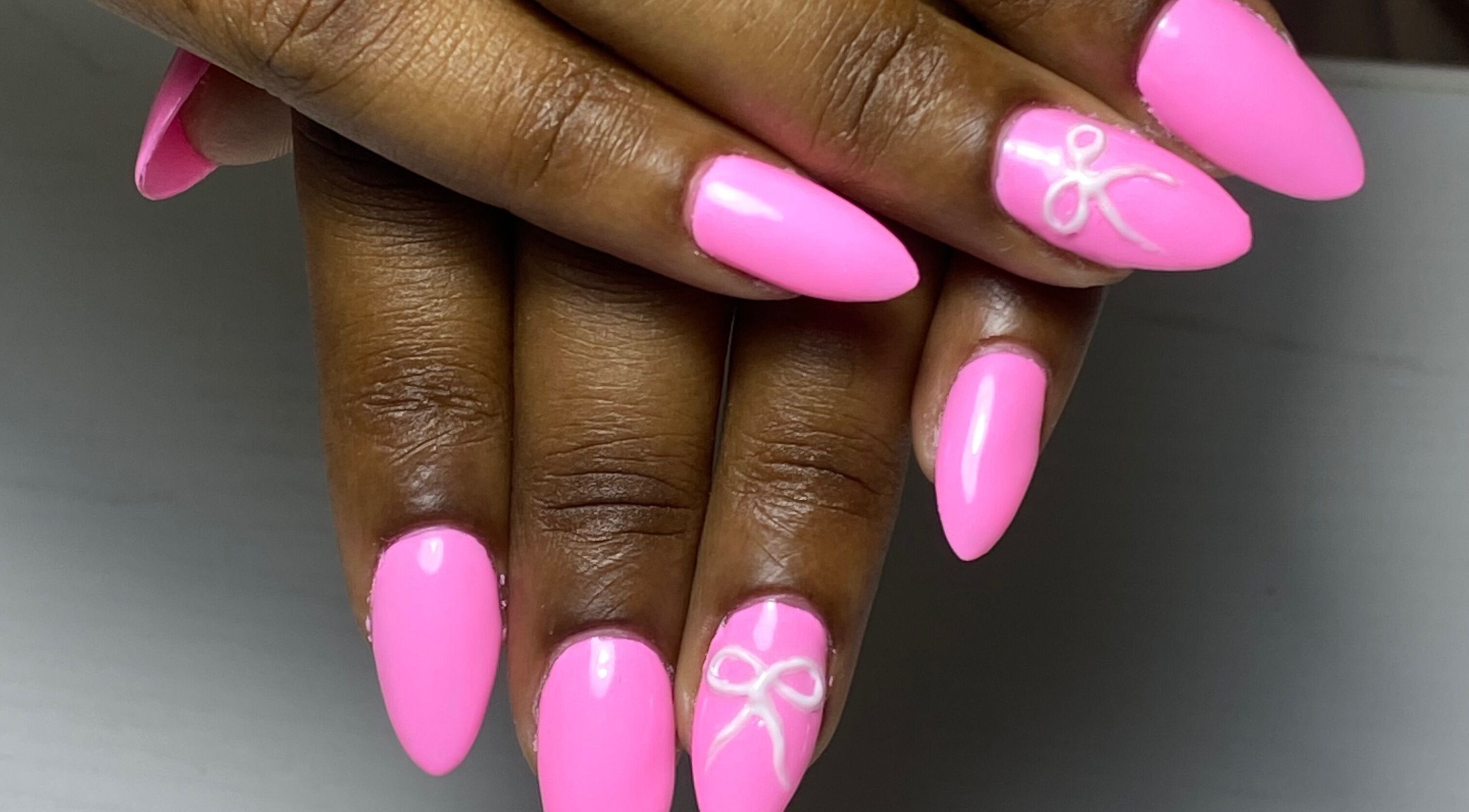 Bright pink nails with bow detail at Glossy in Paramaribo, Paramaribo, SR.
