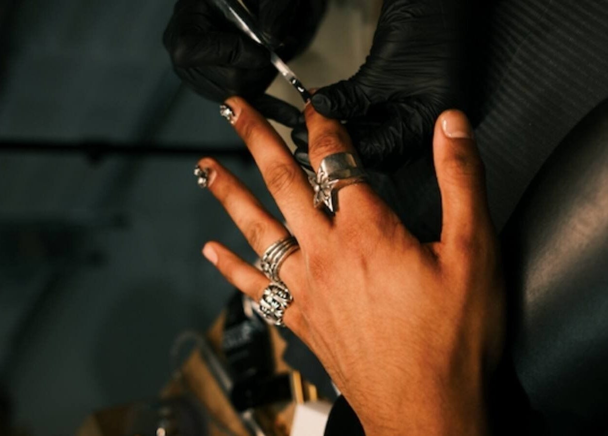 Nail art session at XYZ Beauty Lab, London, England, GB. A hand receives detailed manicure with silver rings.