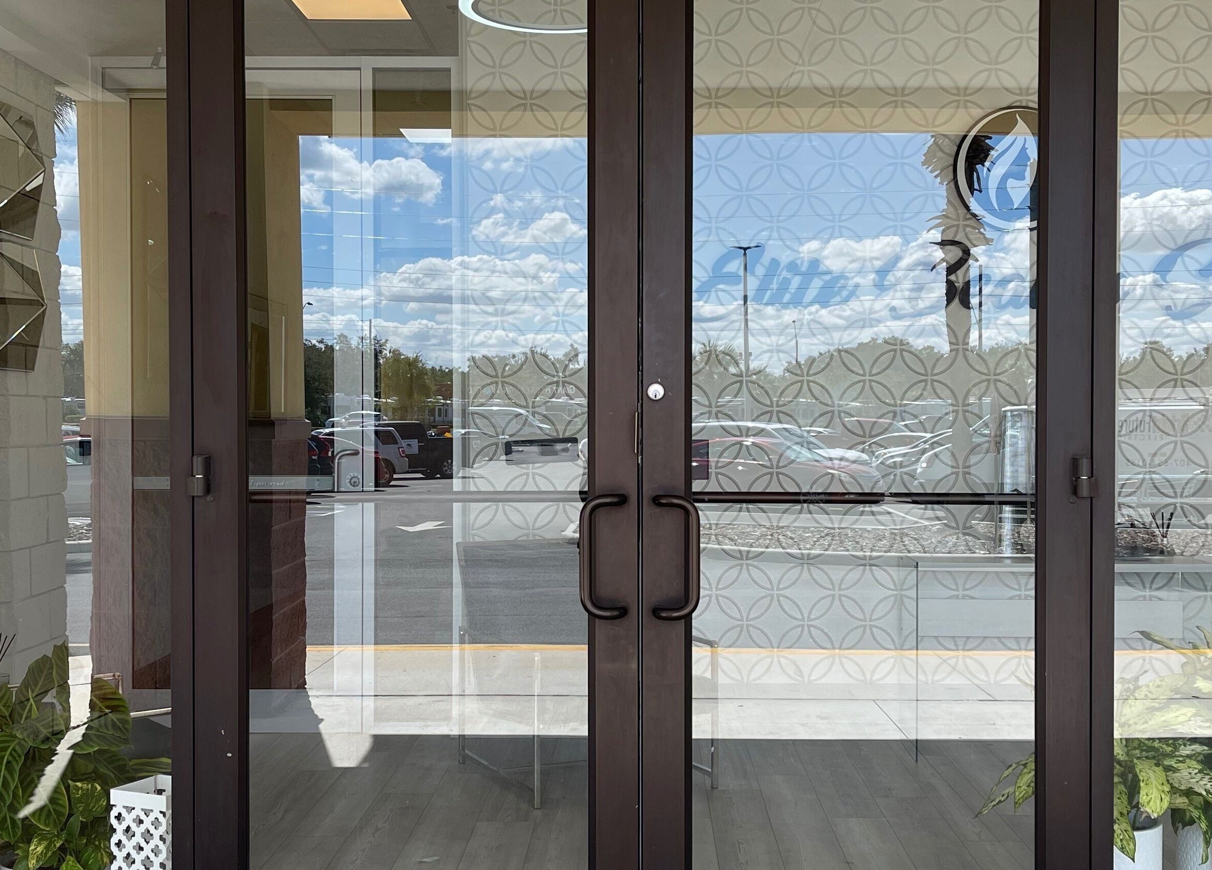 Entrance of Alta Beauty, Winter Garden, Florida, US featuring glass doors with reflections of clouds and sky.
