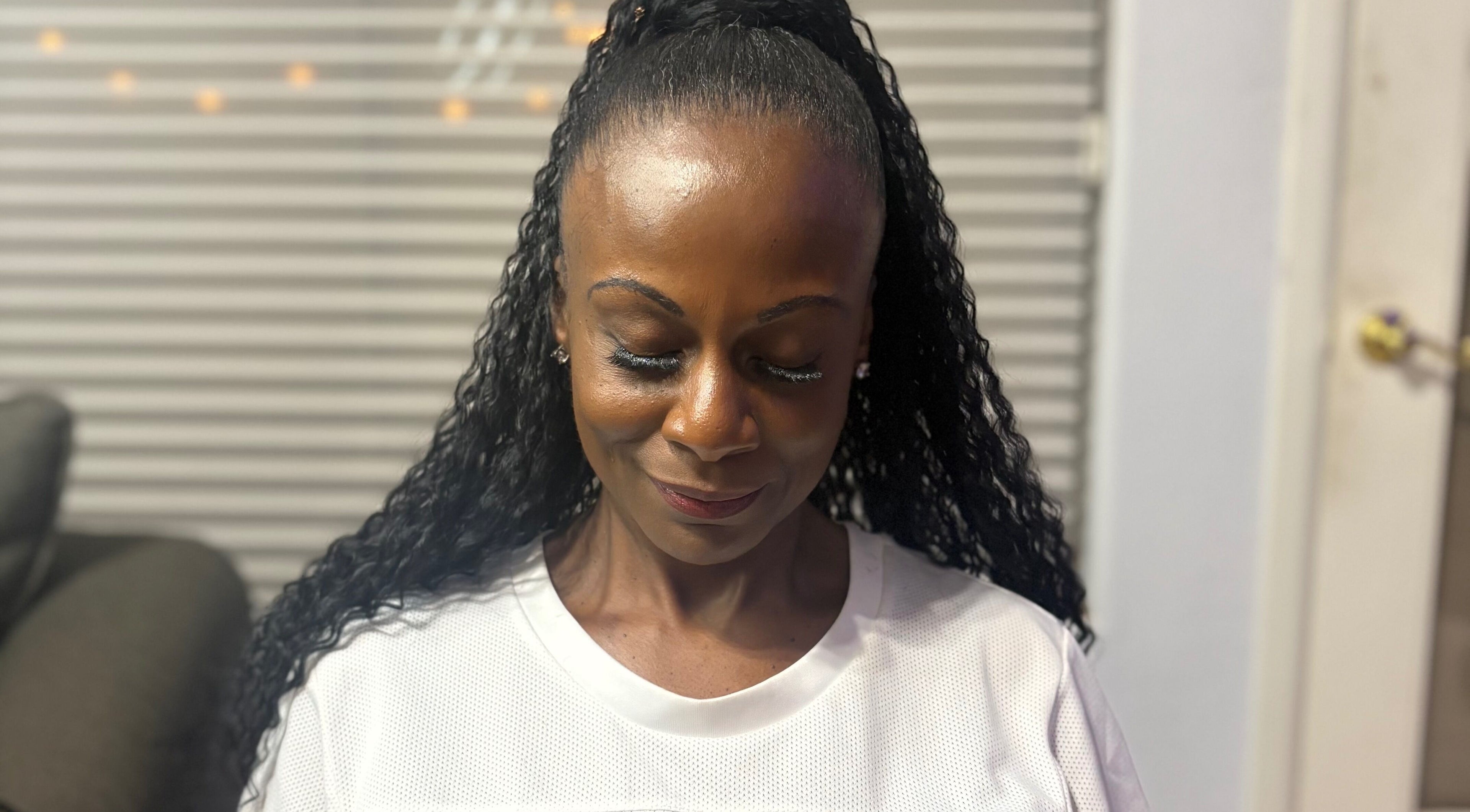 A client with styled hair at CrownedByLanii in El Mirage, Arizona, US, showing calm contentment.