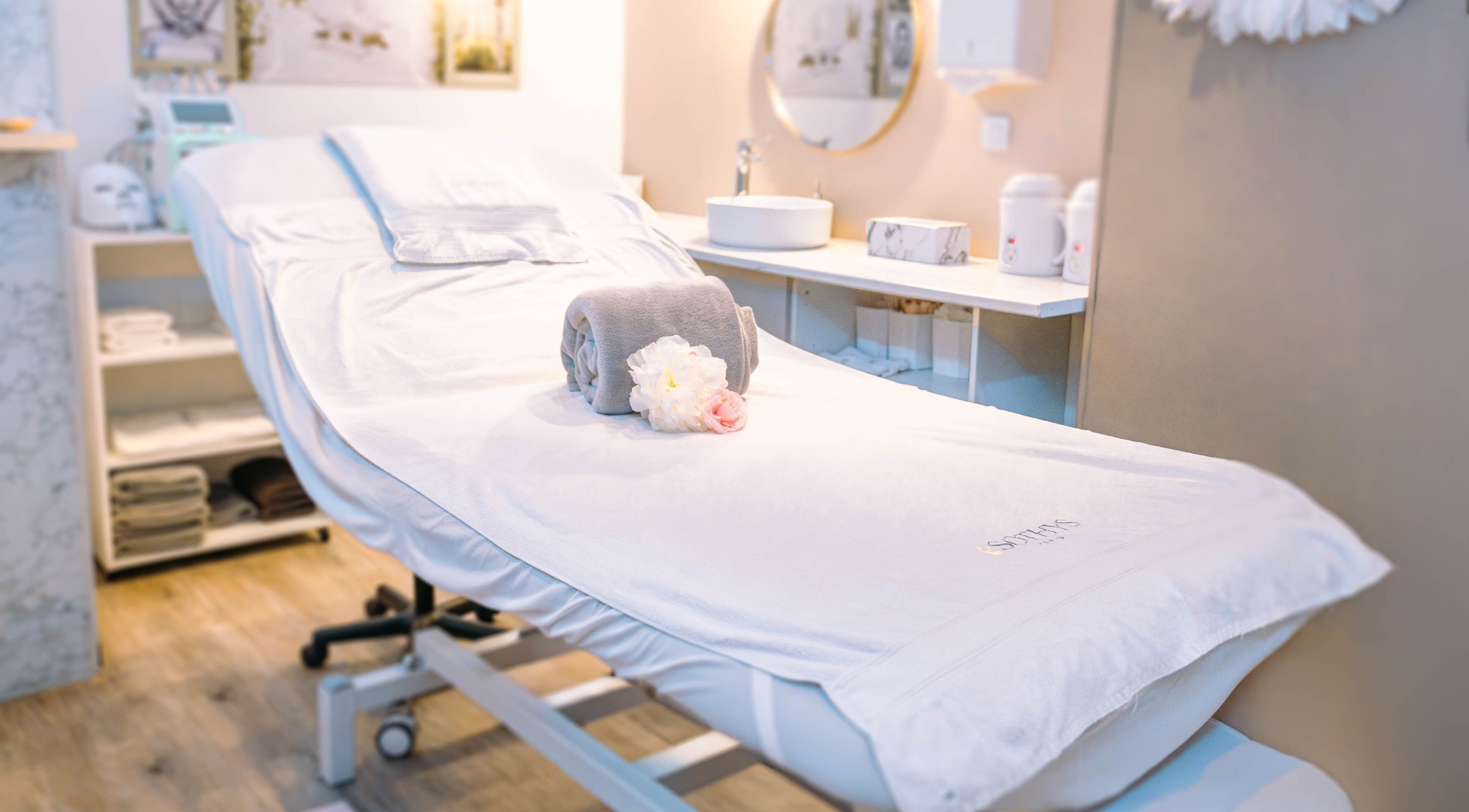 Table de soin relaxante à Beauté Antigone, Montpellier, Occitanie, FR, avec serviette et fleurs.