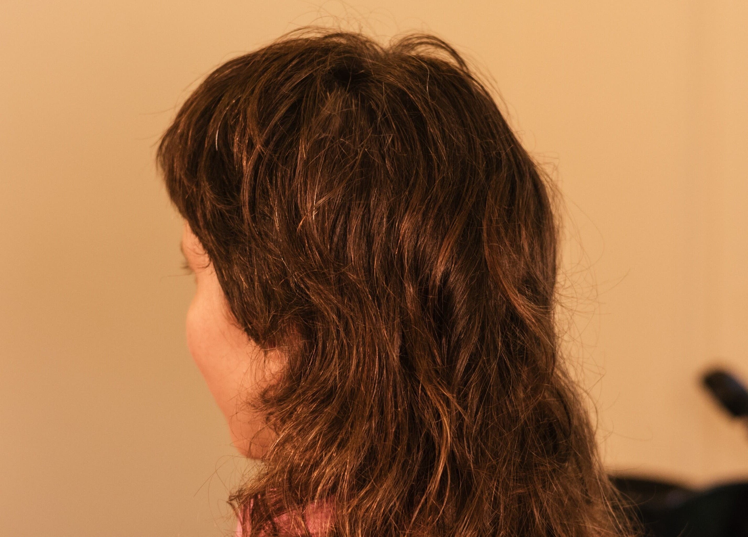 Side profile of a woman with wavy brown hair at nŌta studio, Tulum, Quintana Roo, MX.
