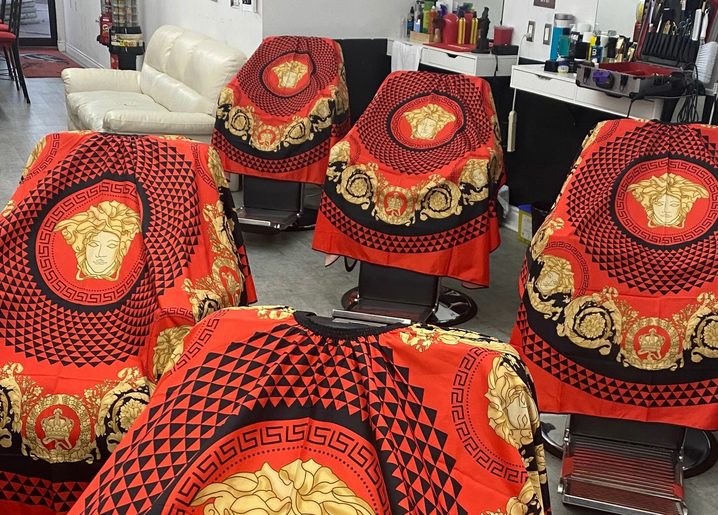 Luxurious red and gold styling capes at Blessed Kutz, Whitby, Ontario, CA, showcasing elegance and style.