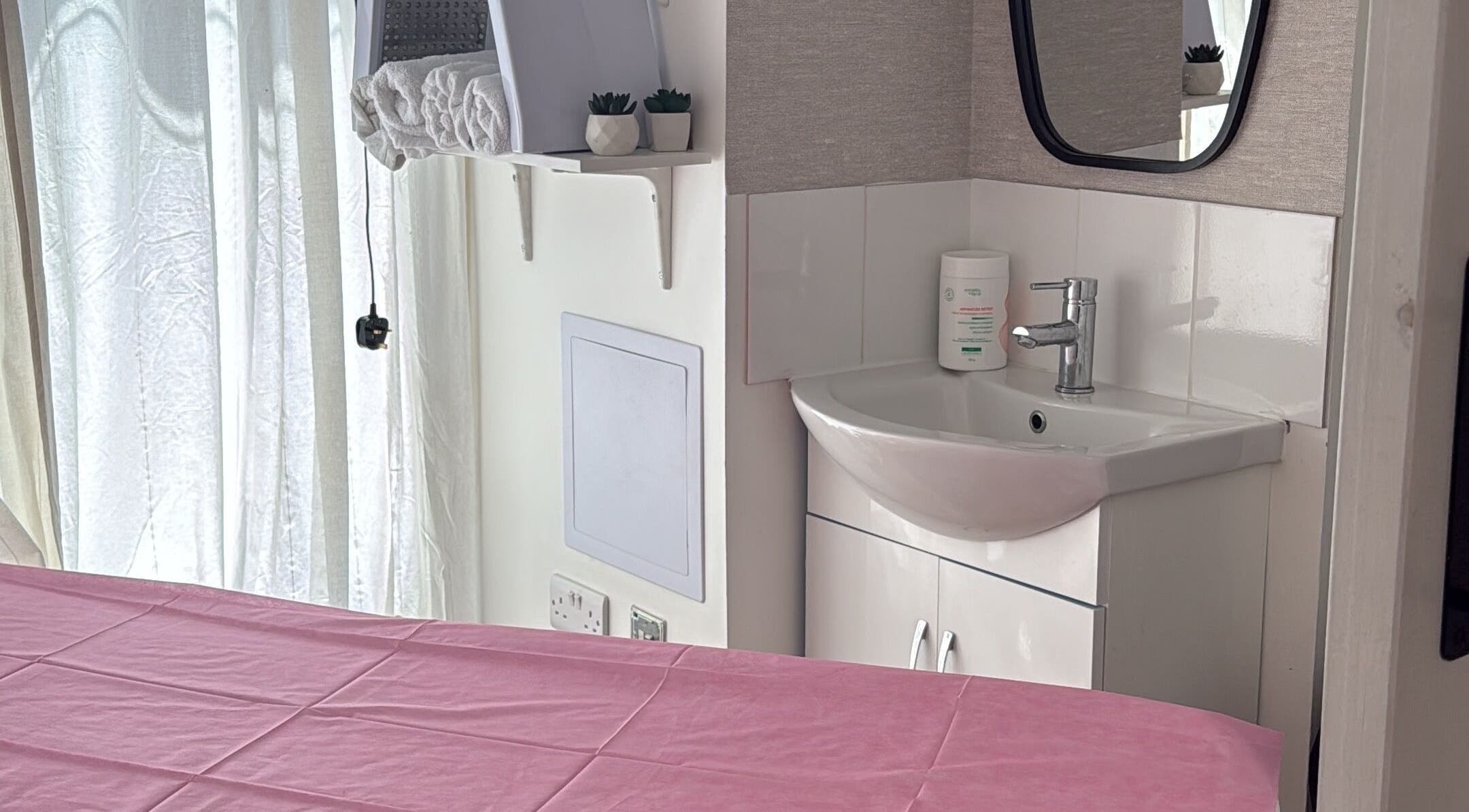 Sala de massagem em Paloma Chinelato, Exeter, England, GB, com mesa e pia.