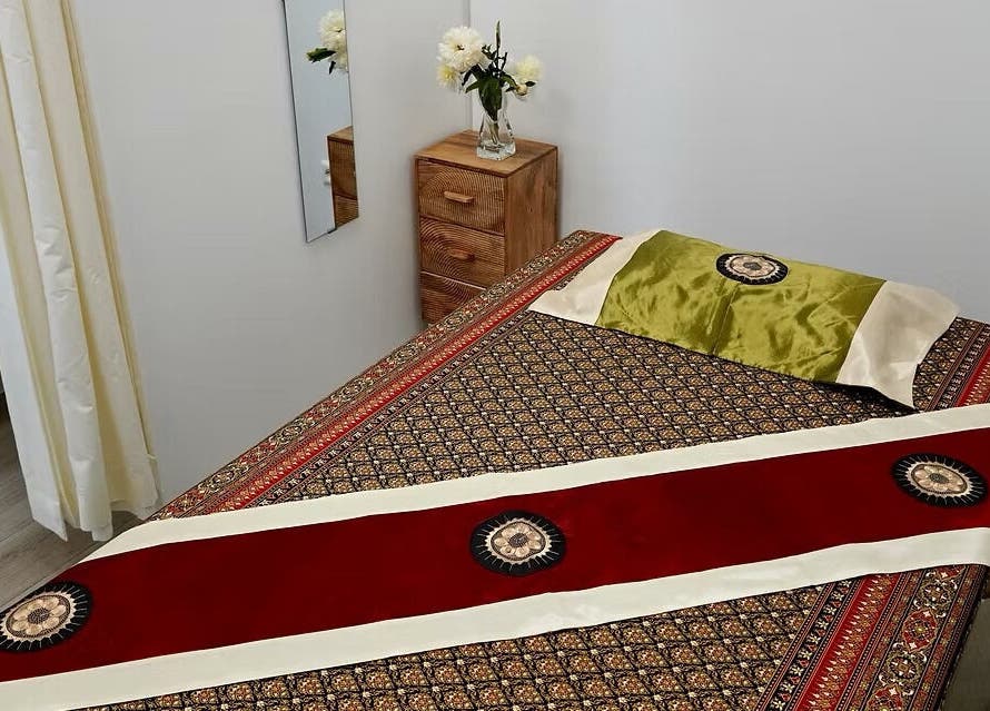 Elegant massage room at Absolute Thai Wellness, Luxembourg, LU, featuring traditional Thai decor and flowers.