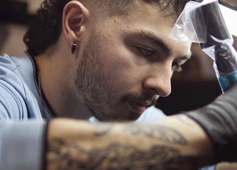 Artiste à Jordan Tattoo, Rimouski, Québec, CA, concentré sur son travail de création détaillée.