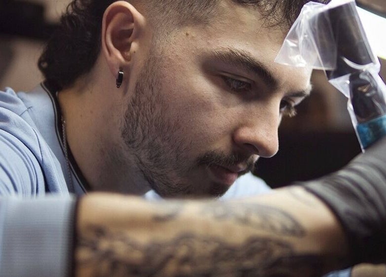 Artiste à Jordan Tattoo, Rimouski, Québec, CA, concentré sur son travail de création détaillée.