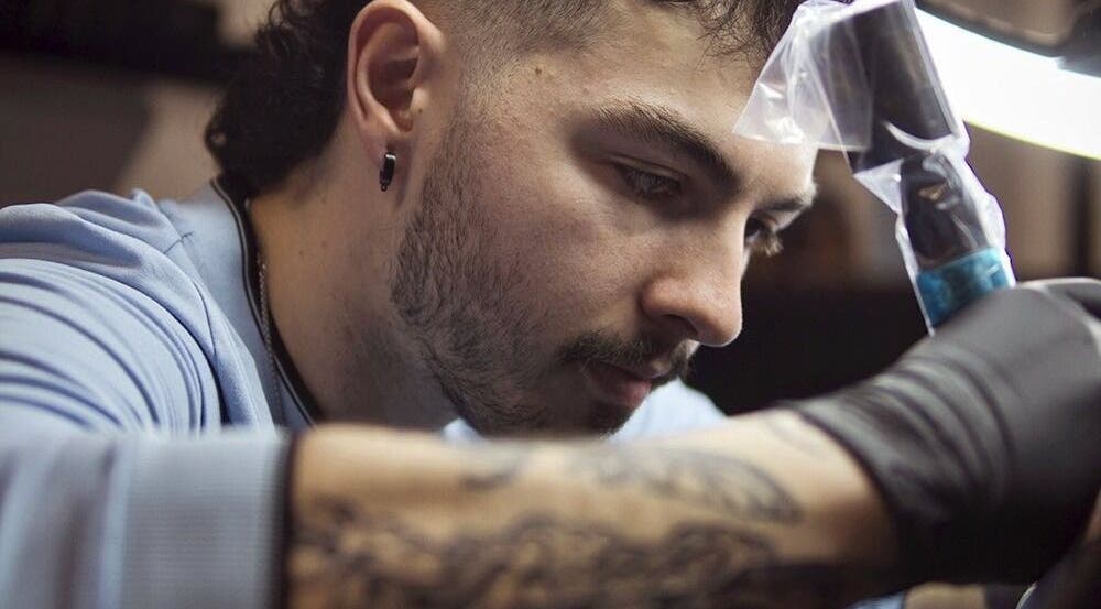 Artiste à Jordan Tattoo, Rimouski, Québec, CA, concentré sur son travail de création détaillée.