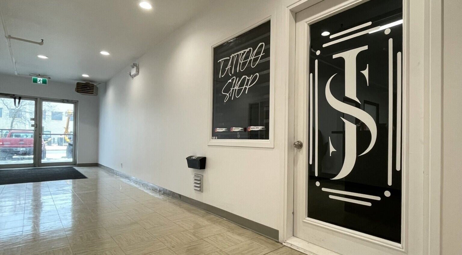 Entrée moderne de Jordan Tattoo à Rimouski, Québec, CA, avec sol brillant et porte vitrée élégante.