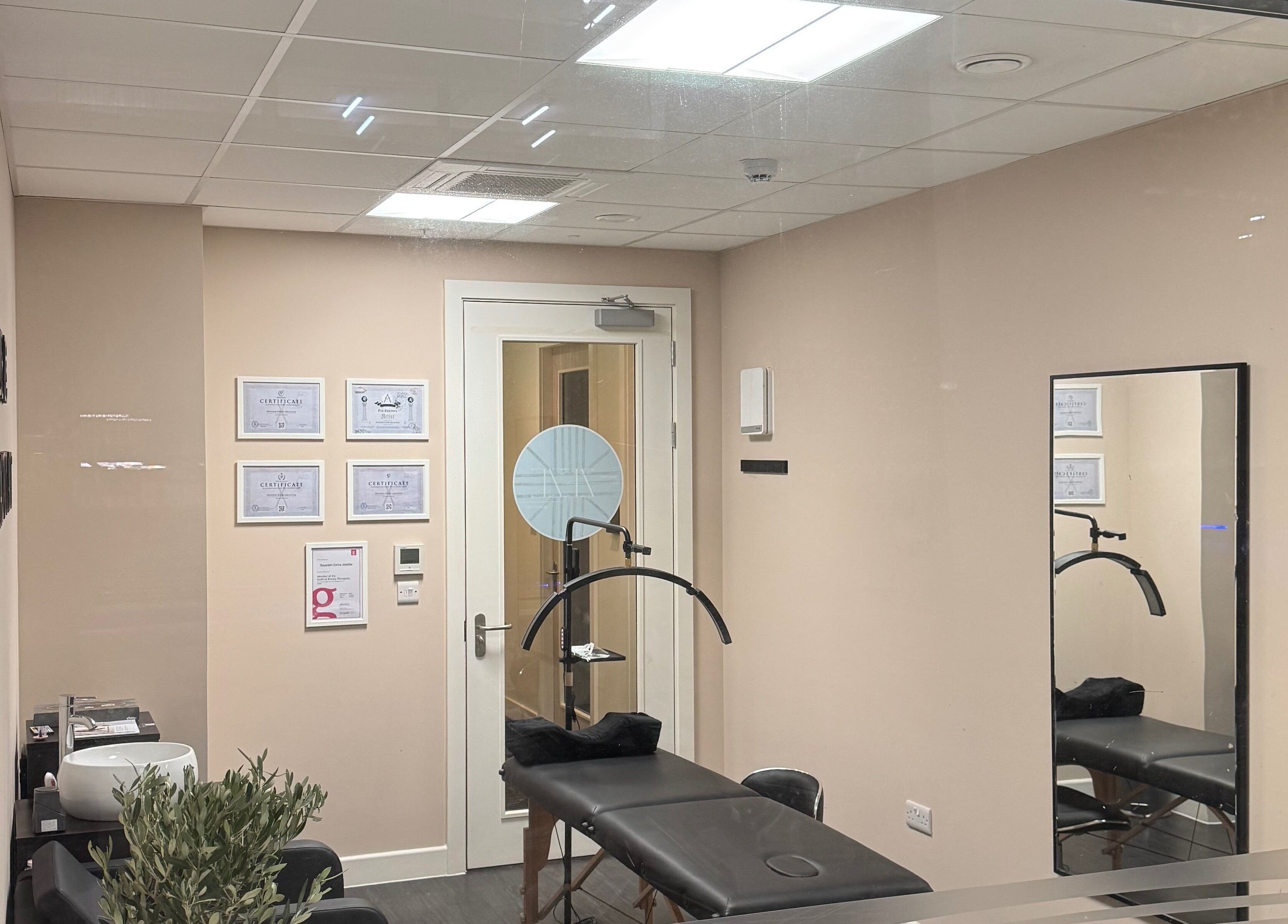 Cozy treatment room at ZeZe Beauty Art, Birmingham, England, GB featuring a massage table and wall certificates.
