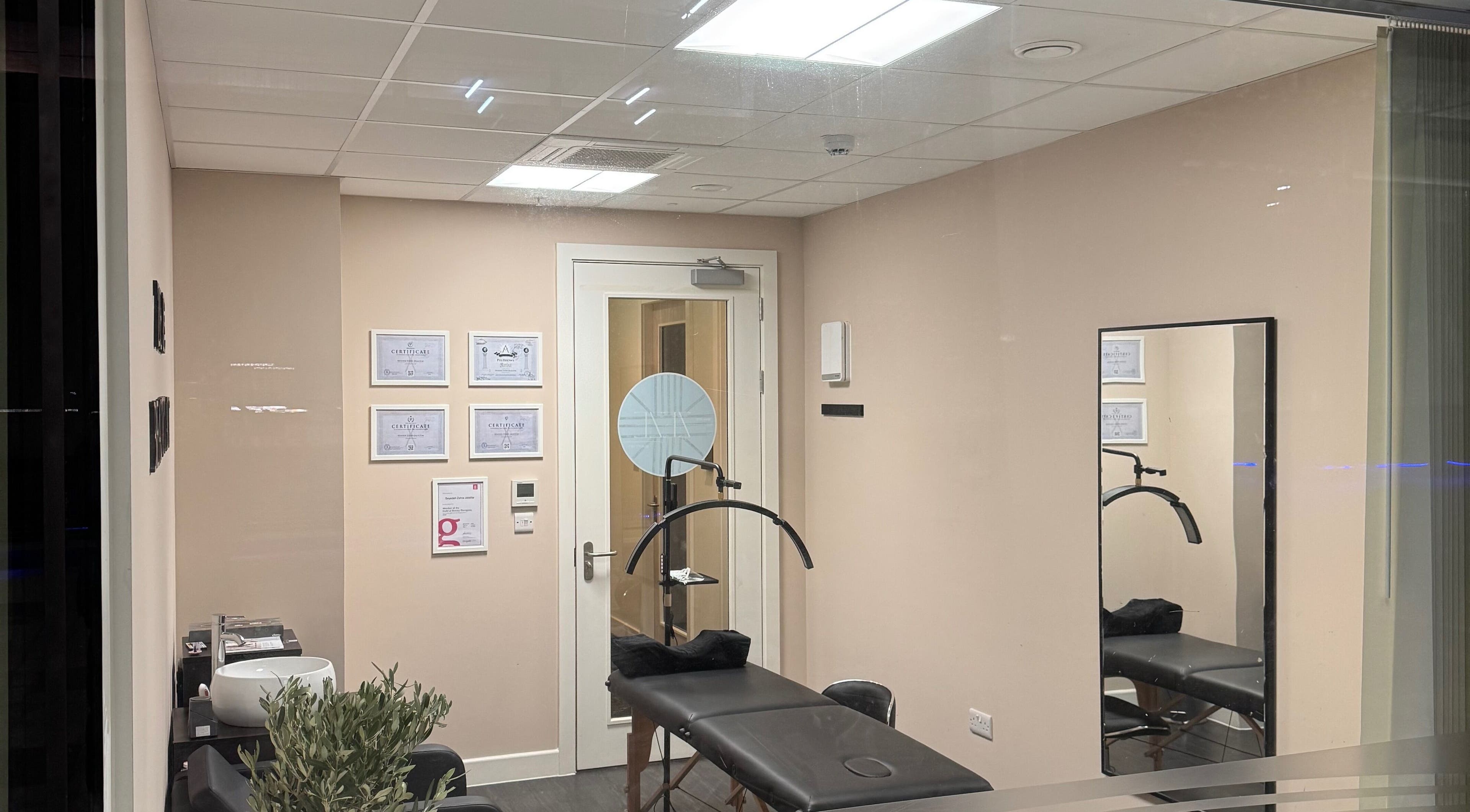 Cozy treatment room at ZeZe Beauty Art, Birmingham, England, GB featuring a massage table and wall certificates.