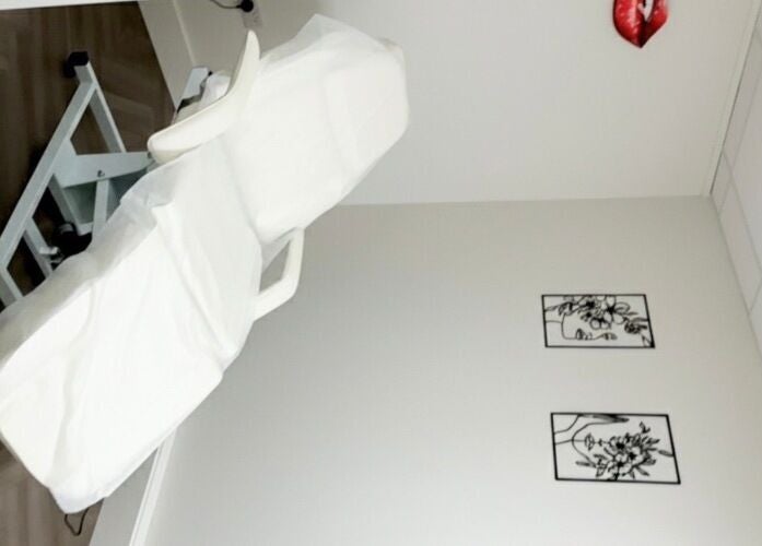 Cozy treatment room at Elya Aesthetic, London, England, GB with a white chair and artistic decor.