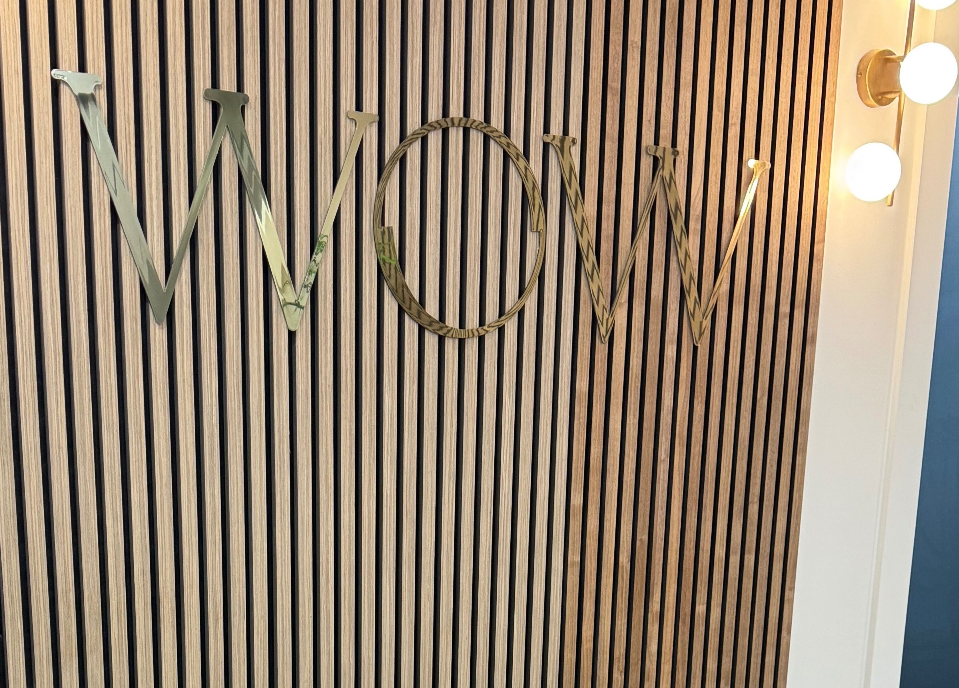 Decorative wall panel with 'WOW' letters at Elya Aesthetic, London, England, GB lit by stylish bulbs.