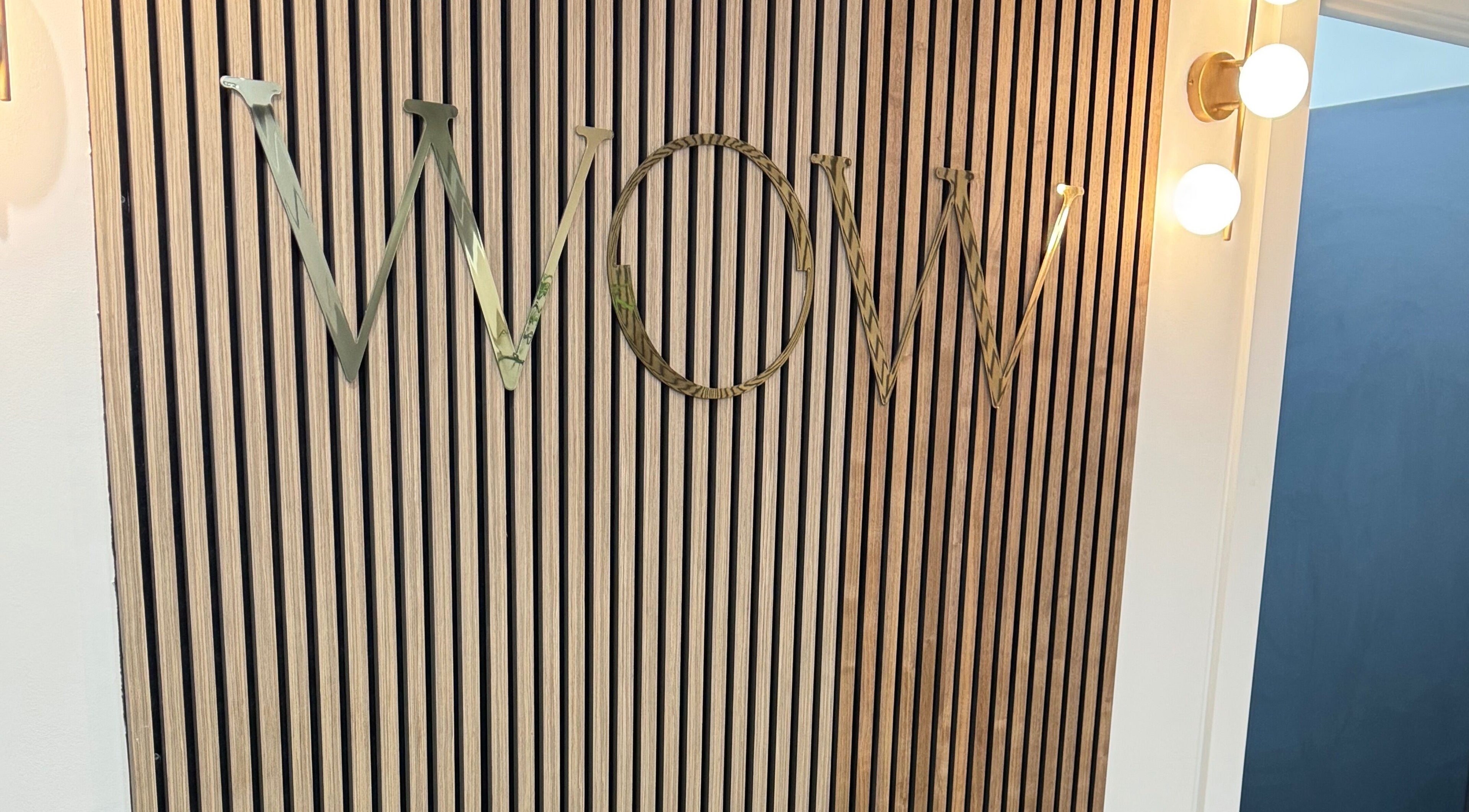 Decorative wall panel with 'WOW' letters at Elya Aesthetic, London, England, GB lit by stylish bulbs.