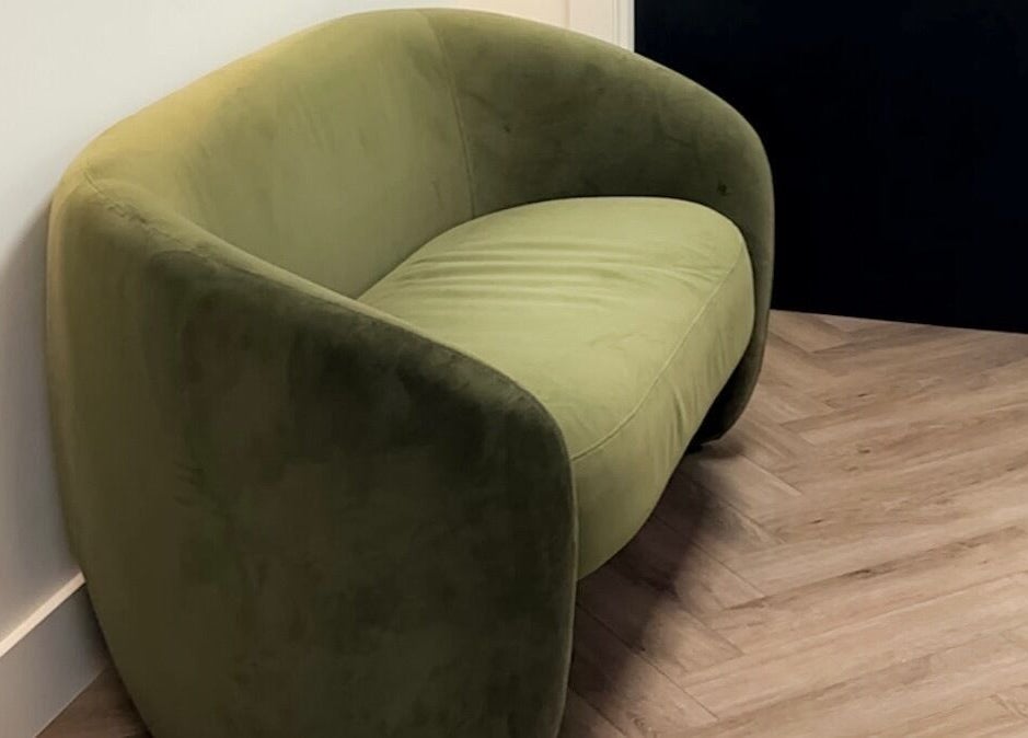 Elegant green couch in Elya Aesthetic, London, England, GB, offering a relaxing atmosphere.