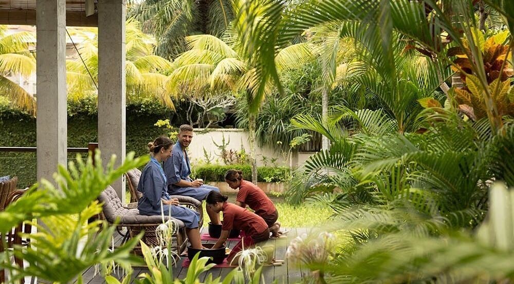 Guests enjoy lush outdoor foot spa at Tejas Spa Bisma, Bali, Bali, ID, surrounded by tropical greenery.