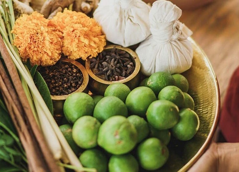 A vibrant herbal platter at Tejas Spa Bisma, Bali, Bali, ID, showcasing fresh limes, spices, and herbal poultices.
