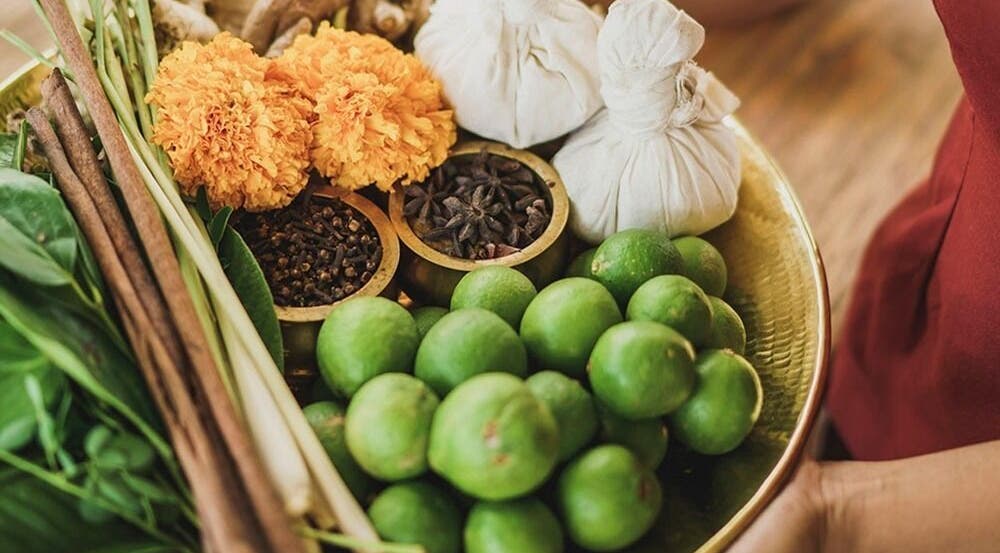 A vibrant herbal platter at Tejas Spa Bisma, Bali, Bali, ID, showcasing fresh limes, spices, and herbal poultices.