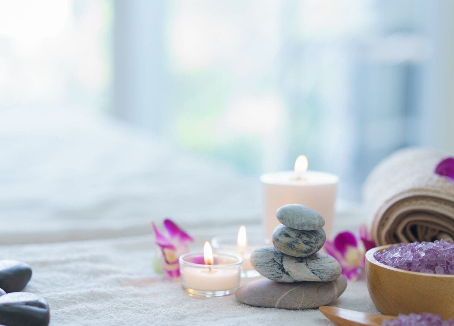 位于马萨诸塞州罗克兰的Harmony Health Spa，展示了一张安静的按摩床，上面放有蜡烛和花瓣。