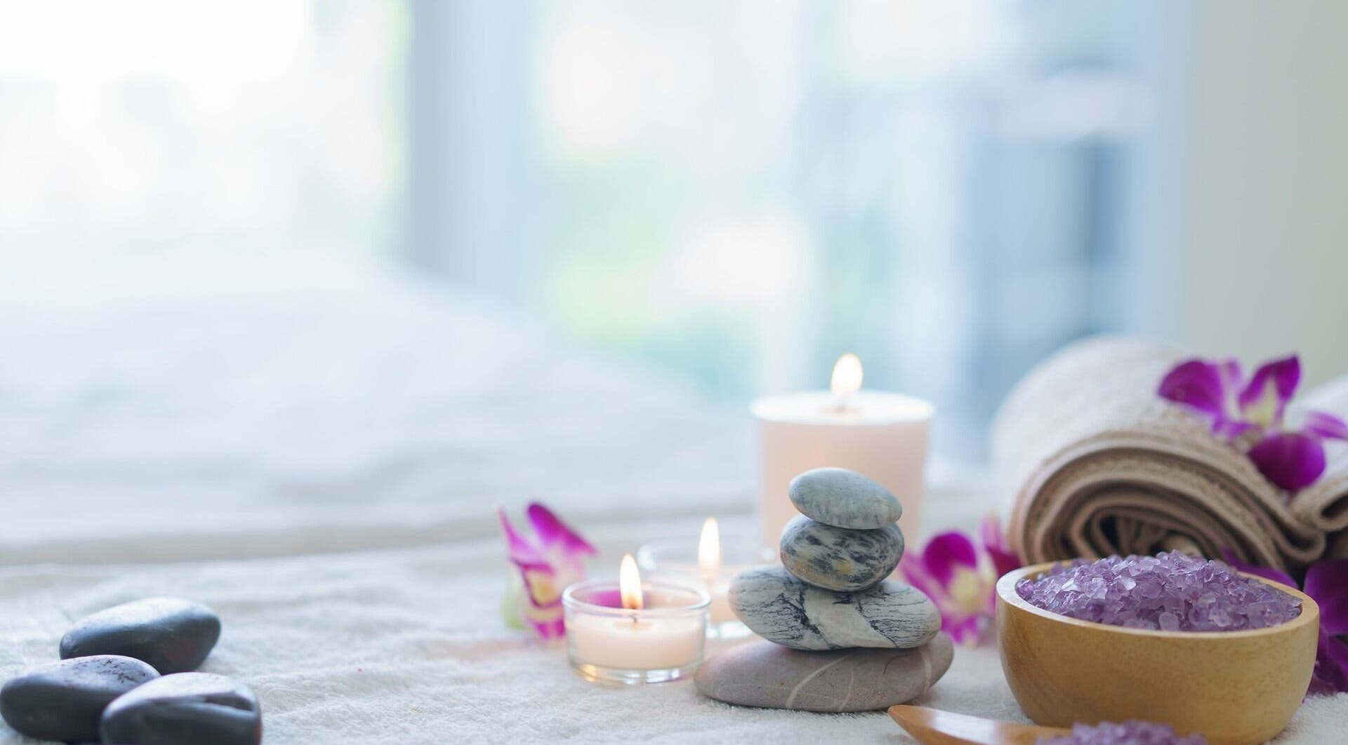 位于马萨诸塞州罗克兰的Harmony Health Spa，展示了一张安静的按摩床，上面放有蜡烛和花瓣。