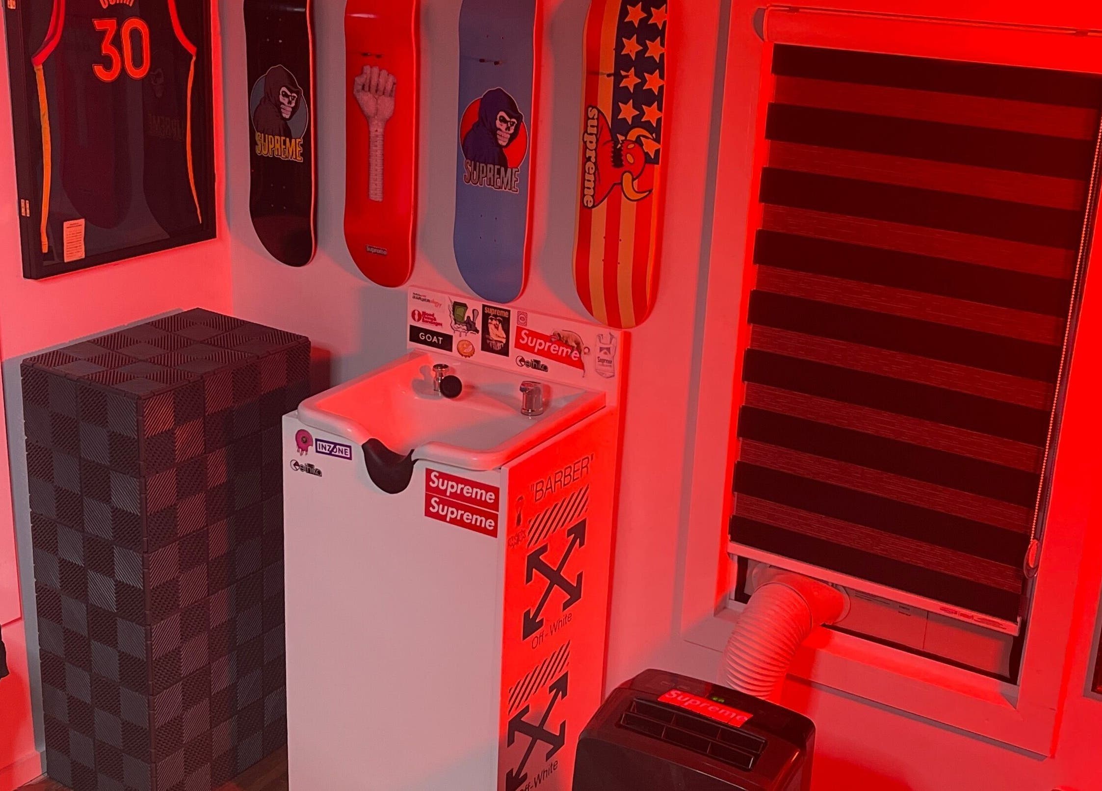 Ricktbarber sink area in Springfield, Massachusetts, US with skateboard decks and red lighting.