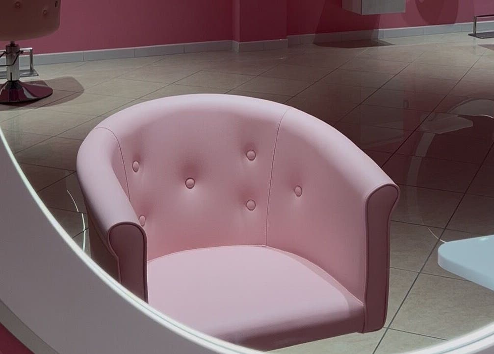 Poltrona rosa pastello presso The Barber Woman, Sava, Puglia, IT, riflette un'atmosfera sofisticata.