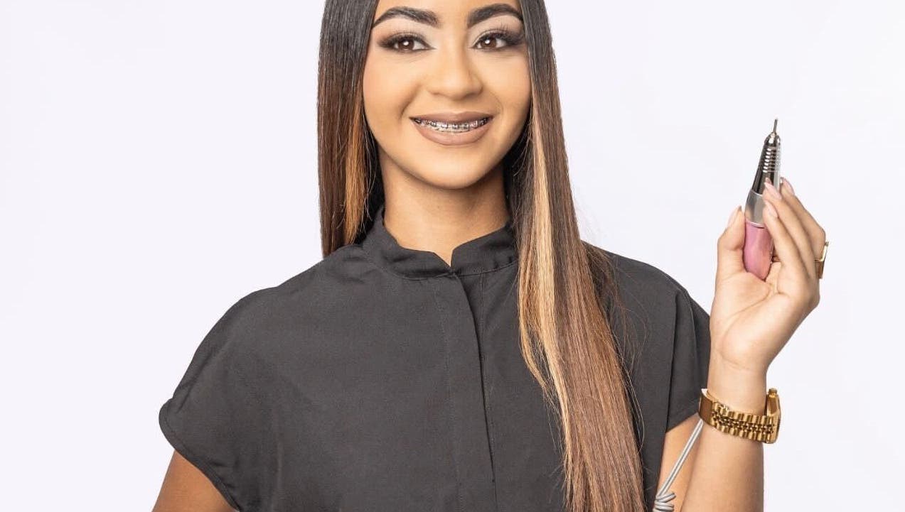 Professional nail artist at Beautybarbygeopr in Vega Alta, PR holding a nail drill tool with a smile.