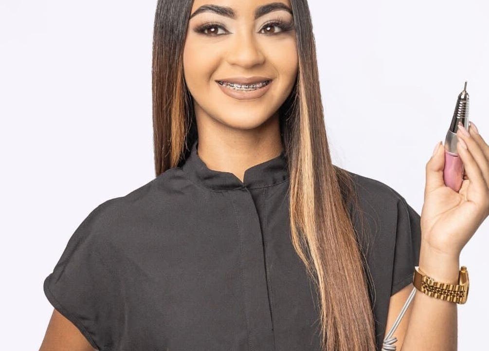 Professional nail artist at Beautybarbygeopr in Vega Alta, PR holding a nail drill tool with a smile.