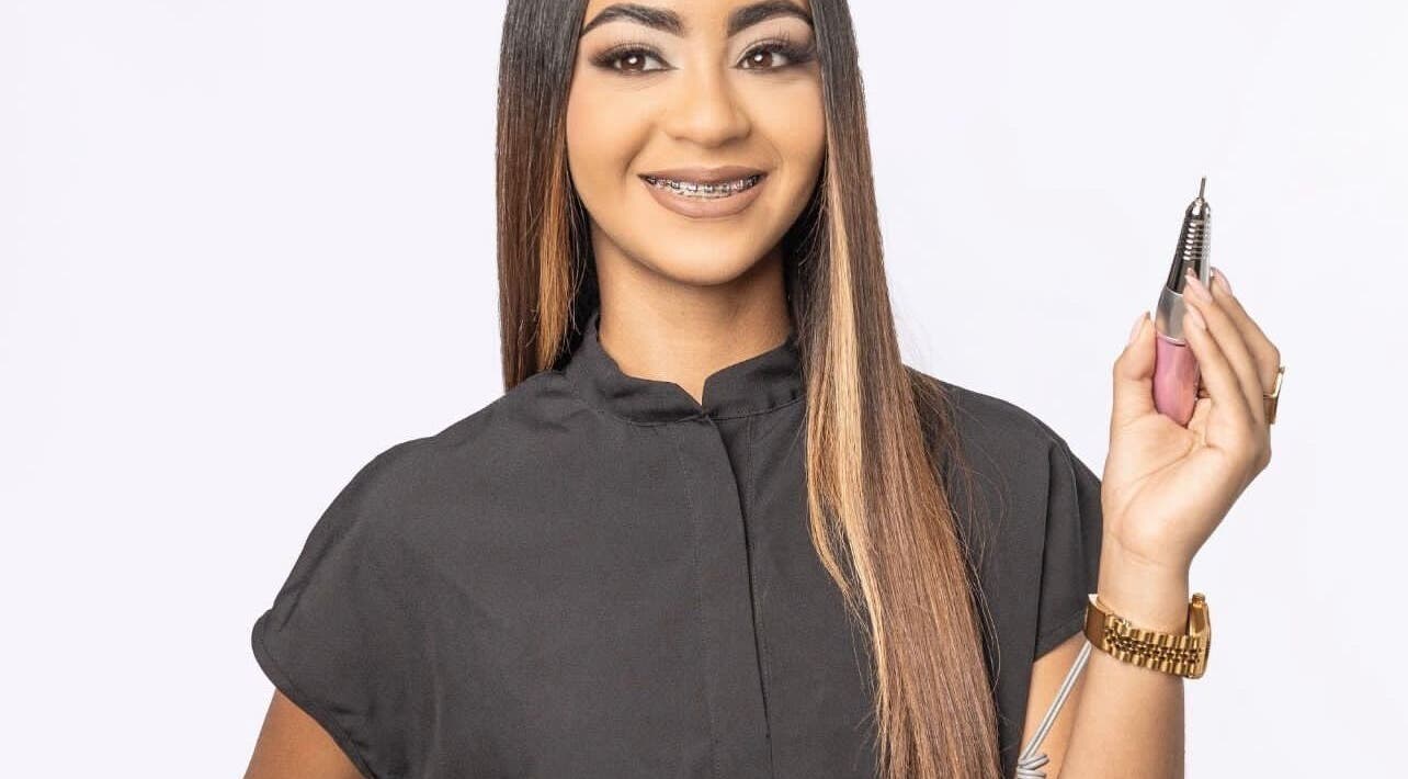 Professional nail artist at Beautybarbygeopr in Vega Alta, PR holding a nail drill tool with a smile.