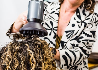 Stylist using a diffuser on curly hair at Curly & Co Hair, Tweed Heads, New South Wales, AU.