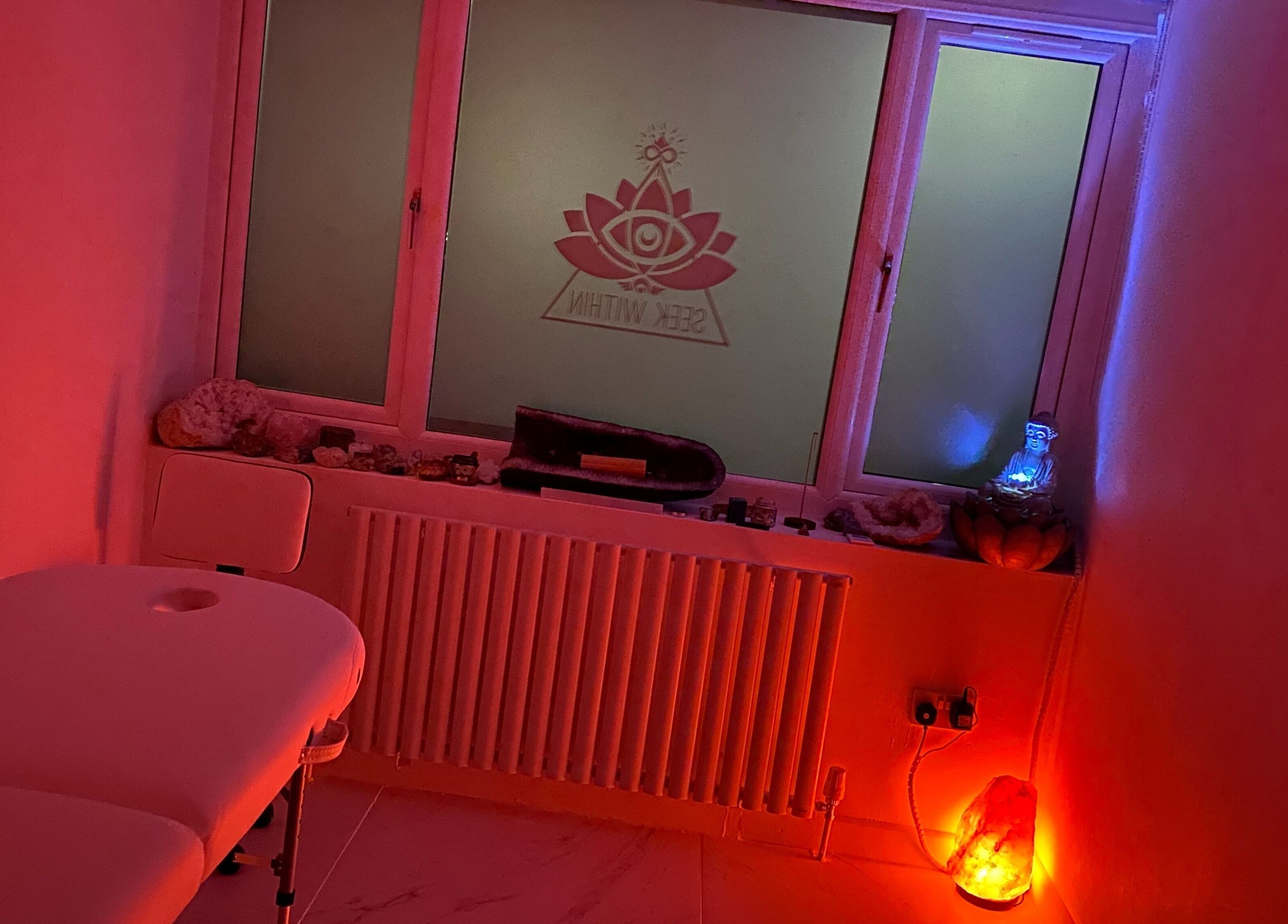 Tranquil massage room at Seek Within, Walsall, England, GB, with calming red lighting and peaceful decor.