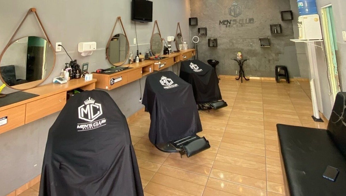 Interior da barbearia Mensclub em Espírito Santo, Espírito Santo, BR com cadeiras modernas e espelhos elegantes.