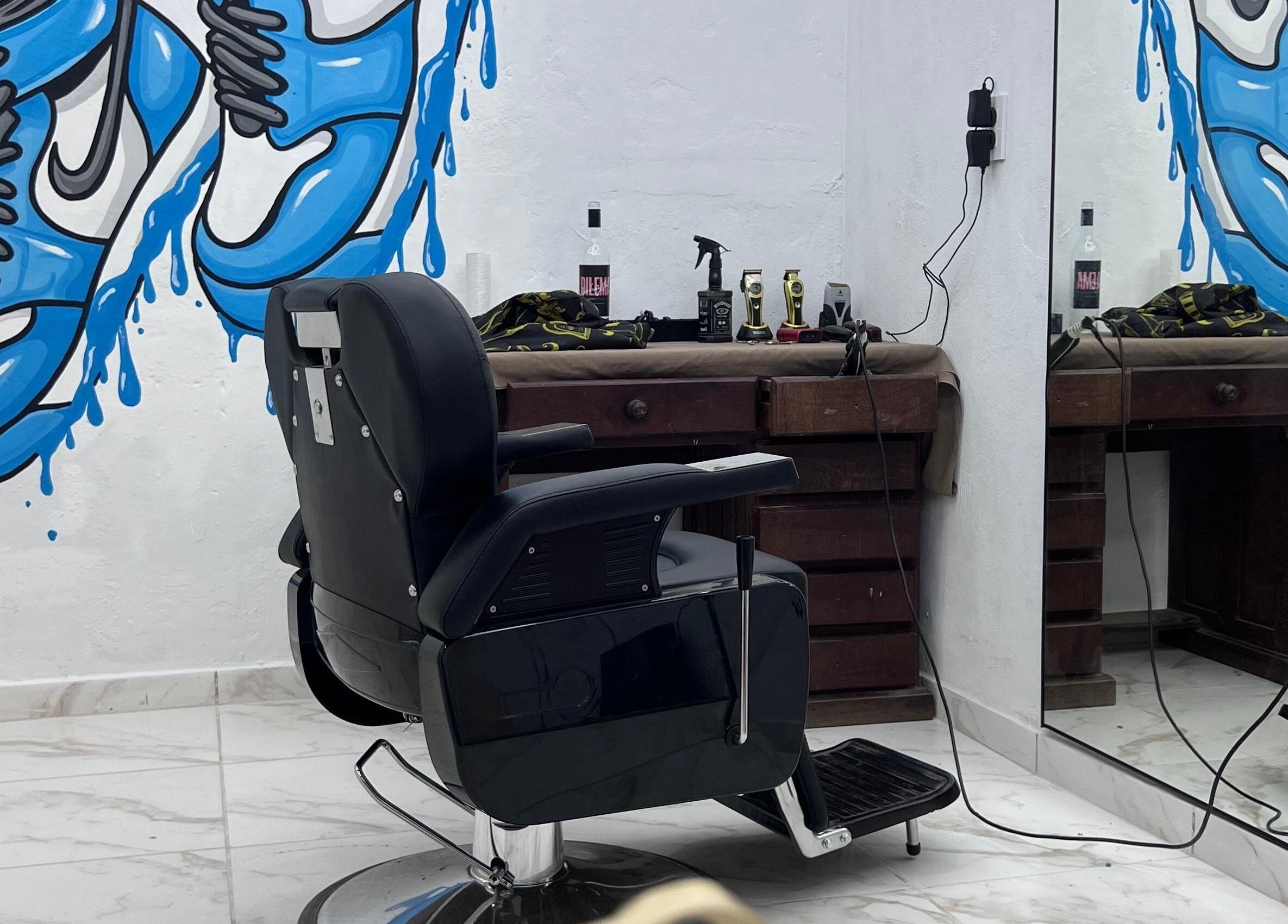 Interior de Hood Barbershop en Villa Gobernador Galvez, Santa Fe, AR con mural vibrante y silla de barbero clásica.