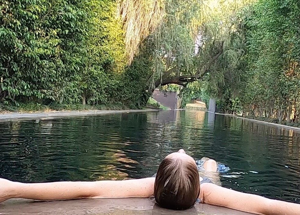 Woman relaxing in serene pool at Lomi Lomi Massage & Meditation, Lisboa, Lisboa, PT, surrounded by lush greenery.