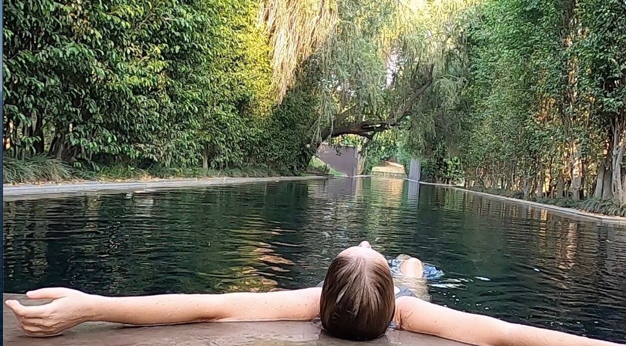 Woman relaxing in serene pool at Lomi Lomi Massage & Meditation, Lisboa, Lisboa, PT, surrounded by lush greenery.