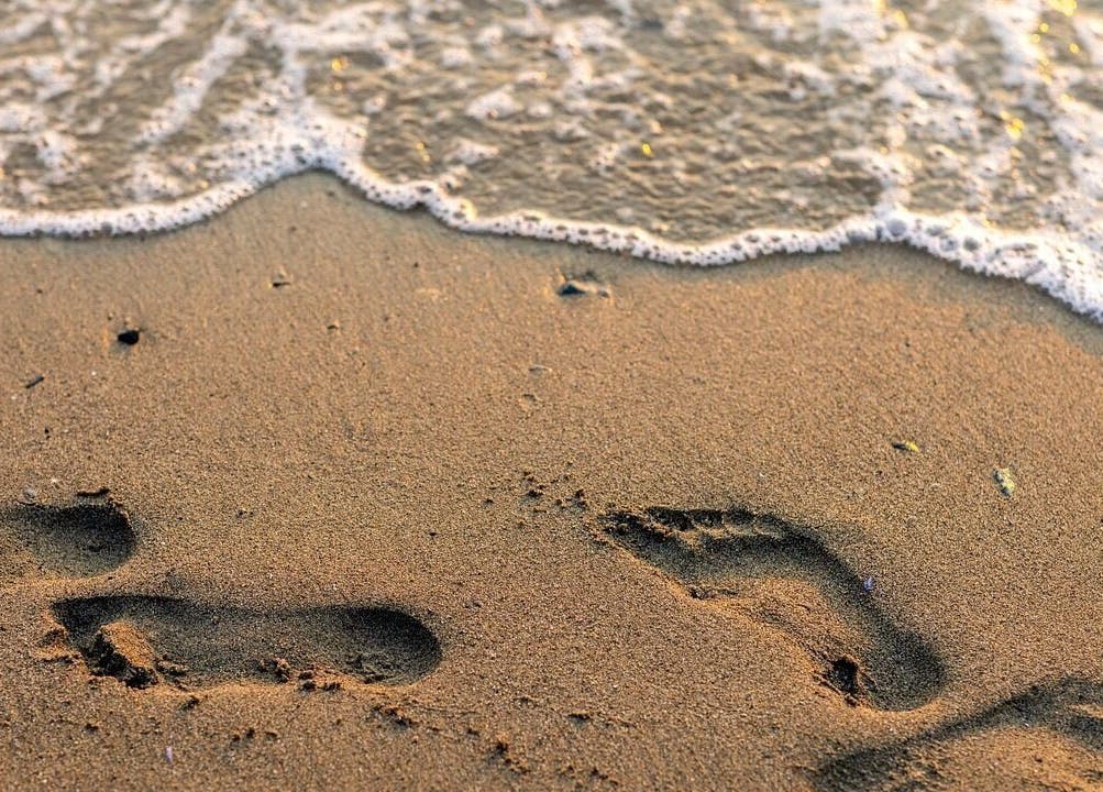 Footprints in sand by the ocean at Lomi Lomi Massage & Meditation, Lisboa, Lisboa, PT.