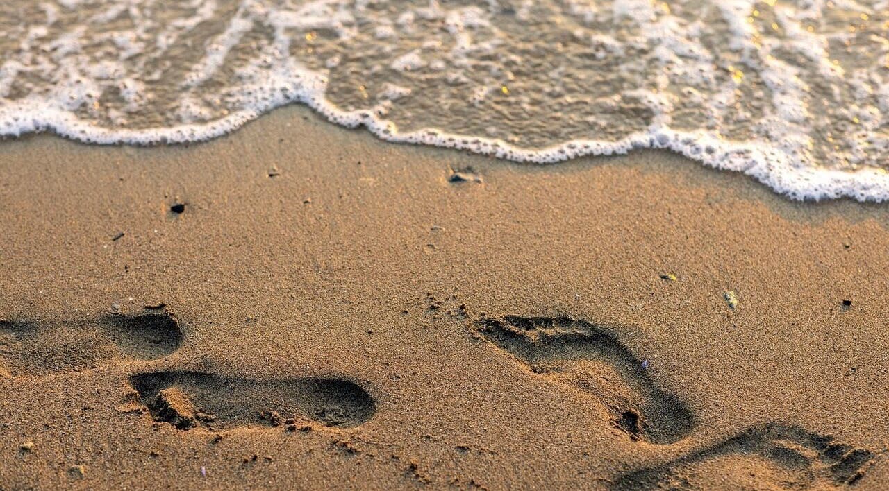 Footprints in sand by the water at Lomi Lomi Massage & Meditation, Lisboa, Lisboa, PT.