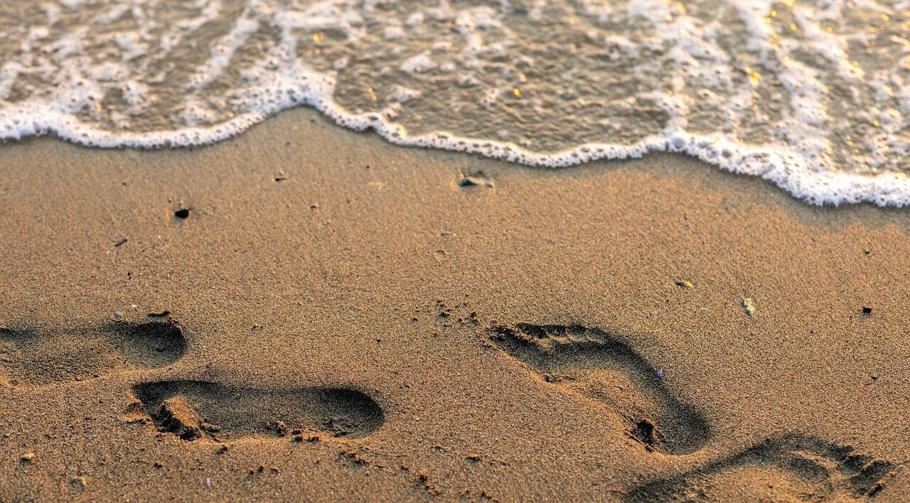 Footprints in sand by the water at Lomi Lomi Massage & Meditation, Lisboa, Lisboa, PT.