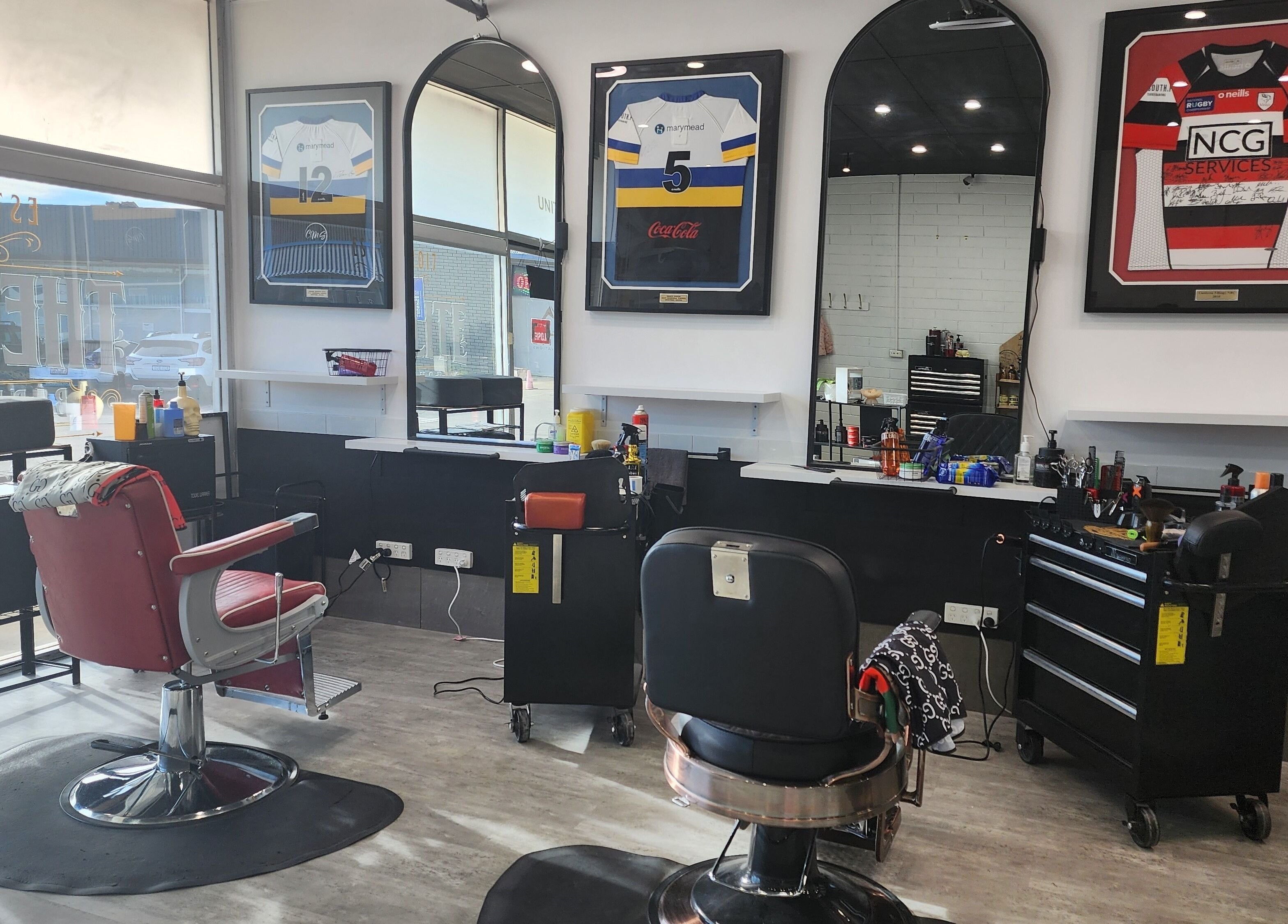 Stylish interior of The Elite Barbershop in Fyshwick, AU, featuring modern barber chairs and framed jerseys.
