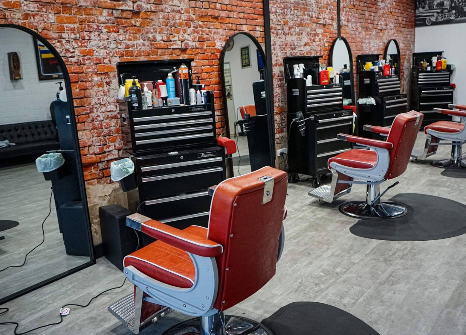 Inside The Elite Barbershop, Fyshwick, AU with vintage chairs and brick walls.