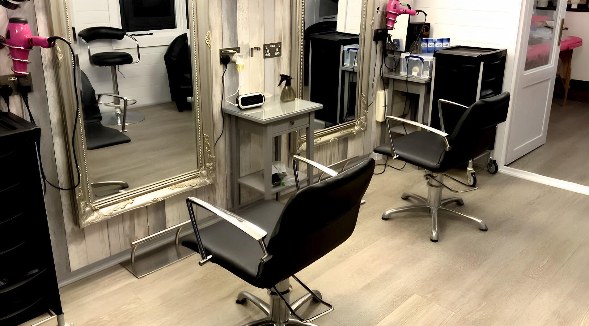 Elegant salon chairs at Hair by Sarah in Bideford, England, GB. Modern styling area with mirrors and hair tools.